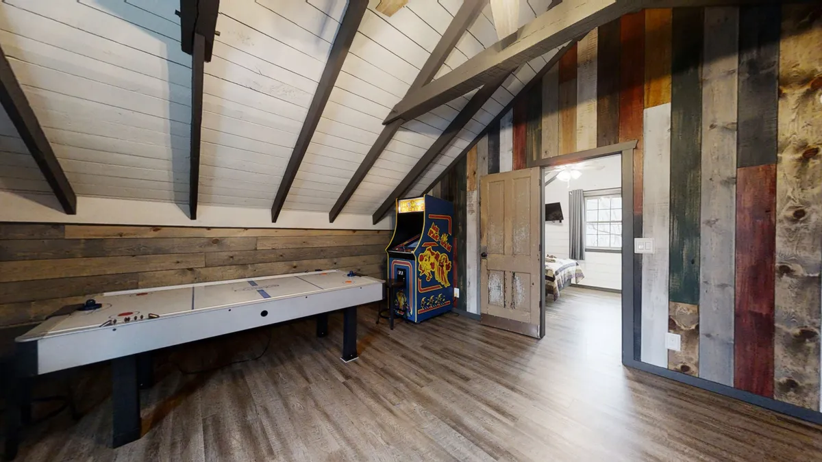 A lively game room featuring an air hockey table, arcade game machine, and a colorful accent wall. The space is clearly designed for fun, with ample room for family competitions and relaxation after a day of exploring local attractions.